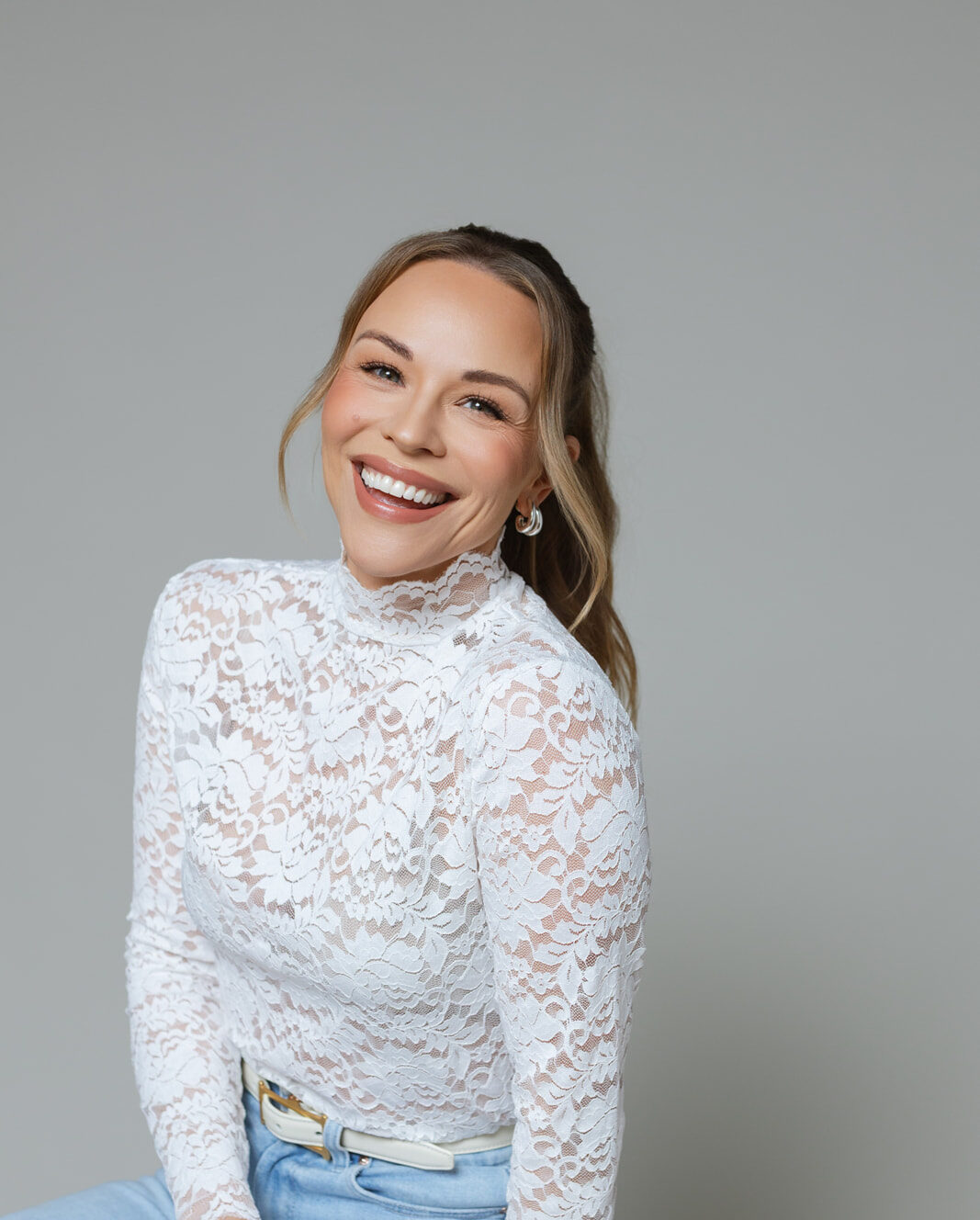 Julie Solomon in a white lace top, laughing