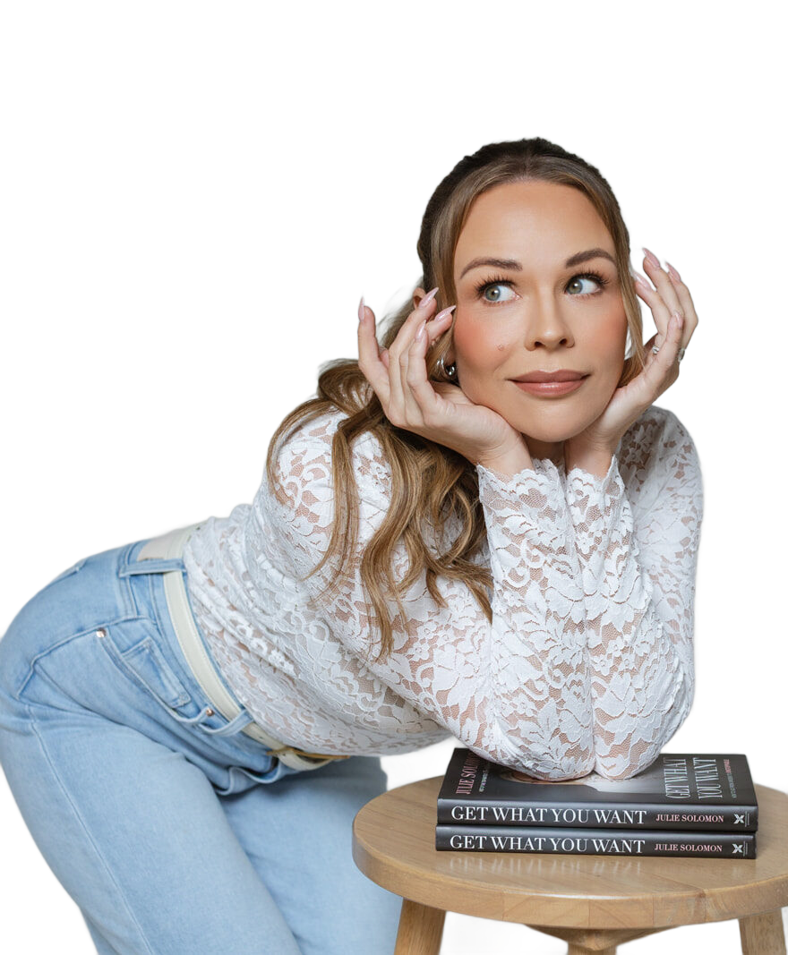 Julie Solomon leaning on a stool beside copies of Get What You Want